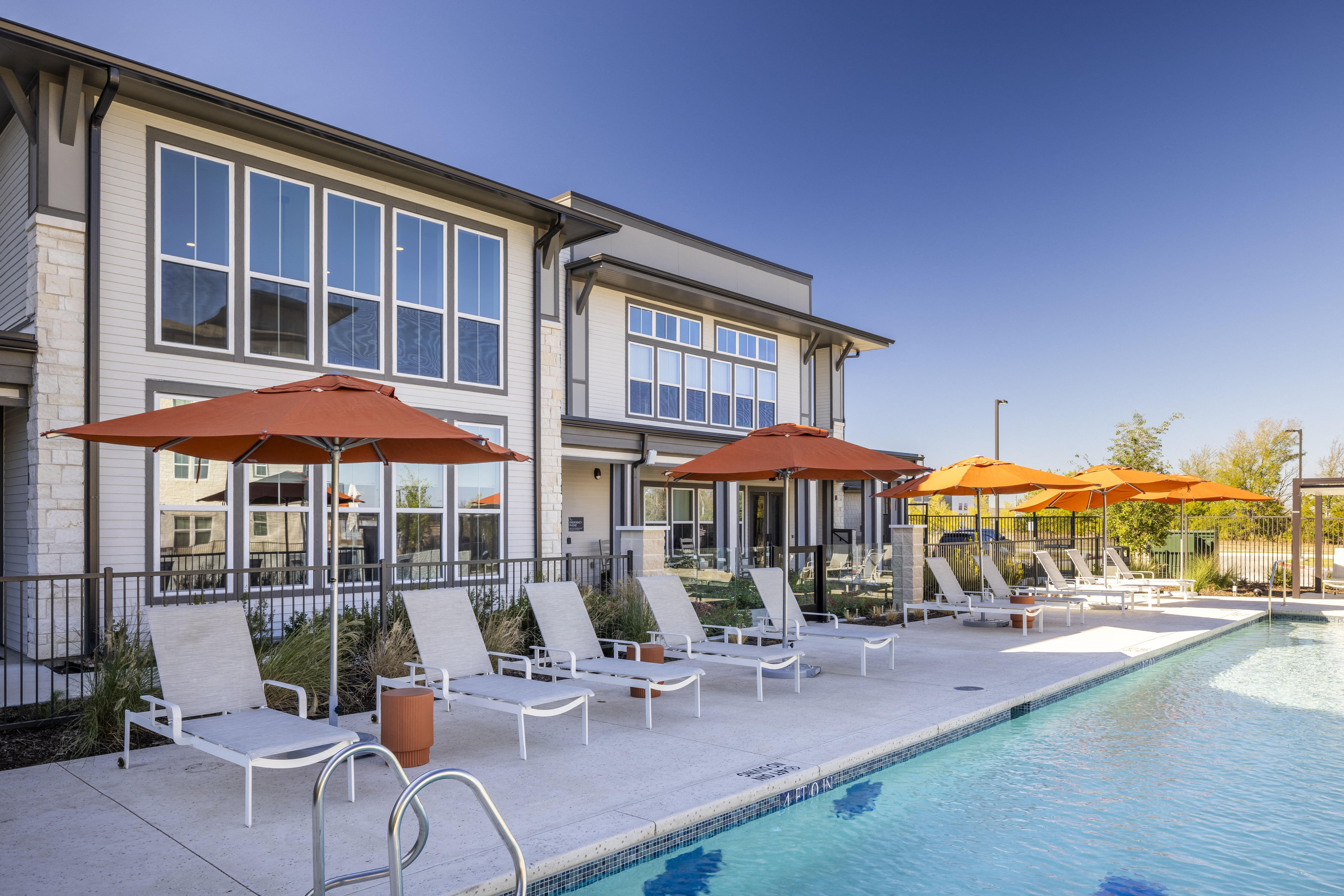 a pool-side image with pool chairs and umbrellas at a senior apartment community